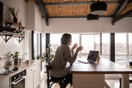 young-woman-chatting-via-laptop-in-kitchen